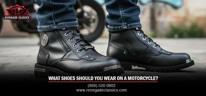 In this image, a man wearing black motorcycle boots with blue jeans stands on the road. The title “What Shoes Should You Wear on a Motorcycle?” with number (888) 520-0802 and www.renegadeclassics.com is shown.