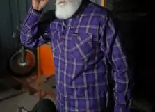 Person wearing a purple plaid shirt in an indoor setting