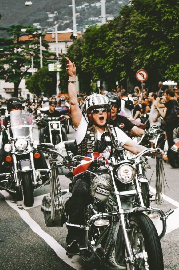 The image features a biker enthusiast proudly riding a motorcycle, wearing a helmet and a vest adorned with patches. The text on the image reads: "RIDE WITH PRIDE - JOIN THE MOTORCYCLE RALLY & FEEL THE FREEDOM".